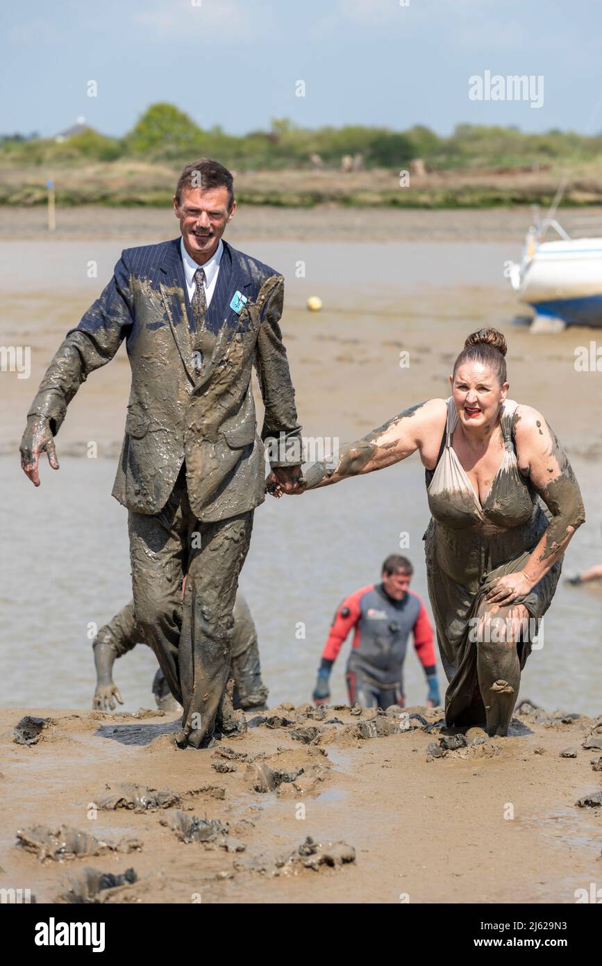 Männlich und weiblich in Hochzeitskleidung beim Maldon Mud Race 2022 auf dem River Blackwater, Essex, Großbritannien. Brautjungfer in Kleid im Schlamm ruiniert Stockfoto