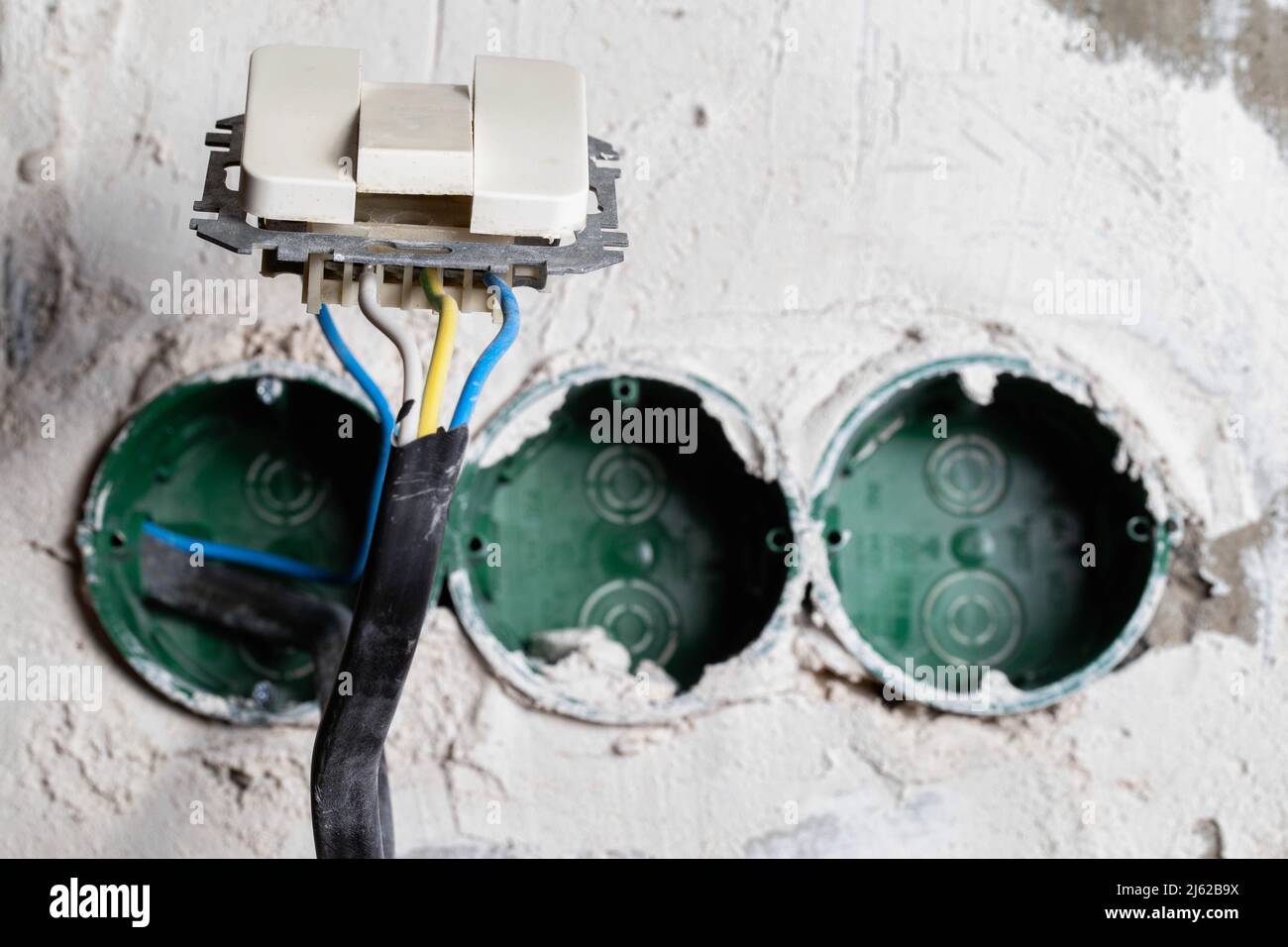 Ein unsicherer elektrischer Schalter hängt an den Kabeln. Elektrische Sicherheit Stockfoto