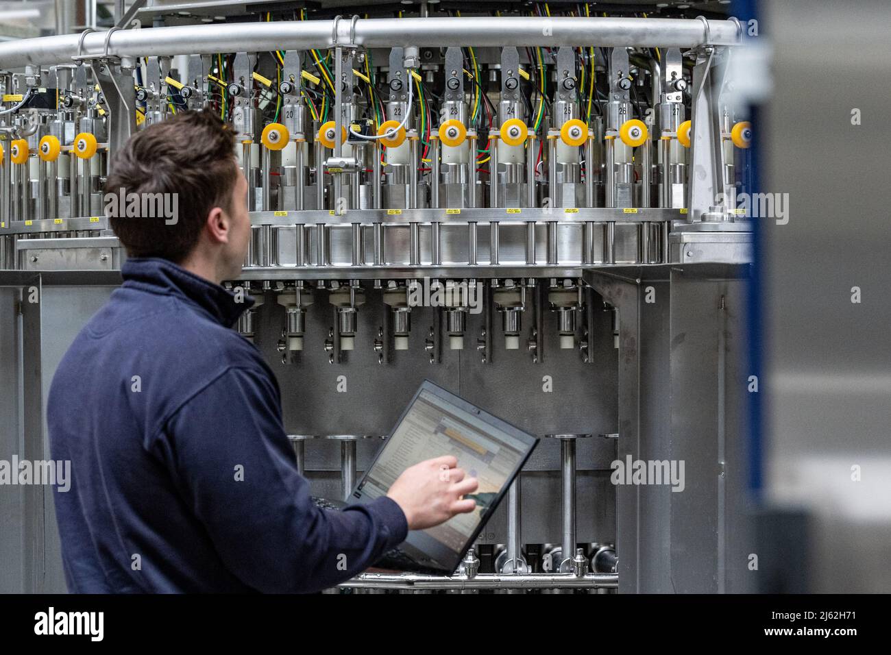 Neutraubling, Deutschland. 25. April 2022. Ein Mitarbeiter der Krones AG arbeitet an einer Abfüllanlage in der Produktion. Quelle: Armin Weigel/dpa/Alamy Live News Stockfoto