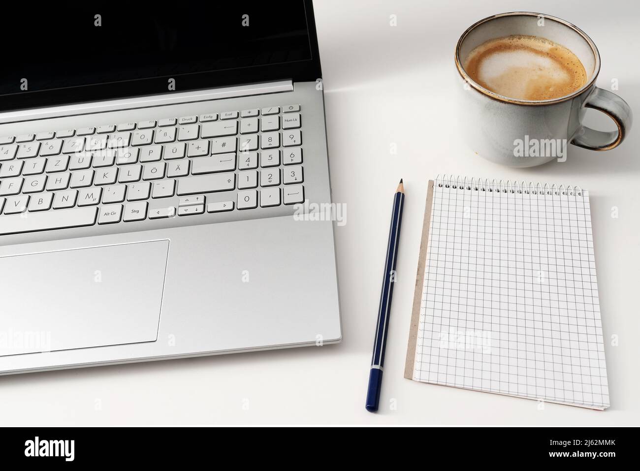 Laptop-Computer und Notizblock auf weißem Schreibtisch mit einer Tasse Kaffee Stockfoto