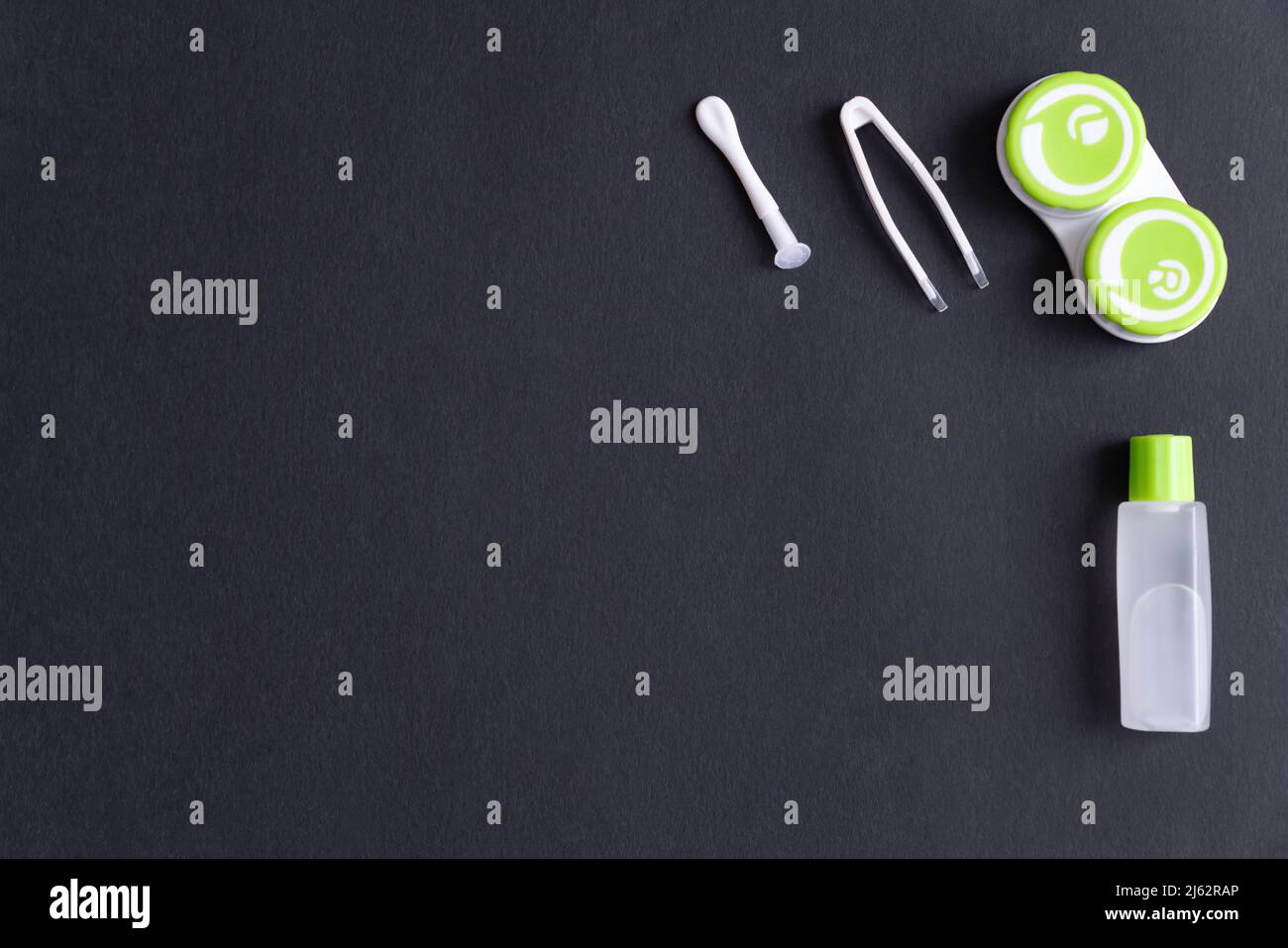 Behälter mit Kontaktlinsen, Pinzette, Saugnapf und Flasche mit Lösung auf schwarzem Hintergrund, Draufsicht, Kopierraum Stockfoto