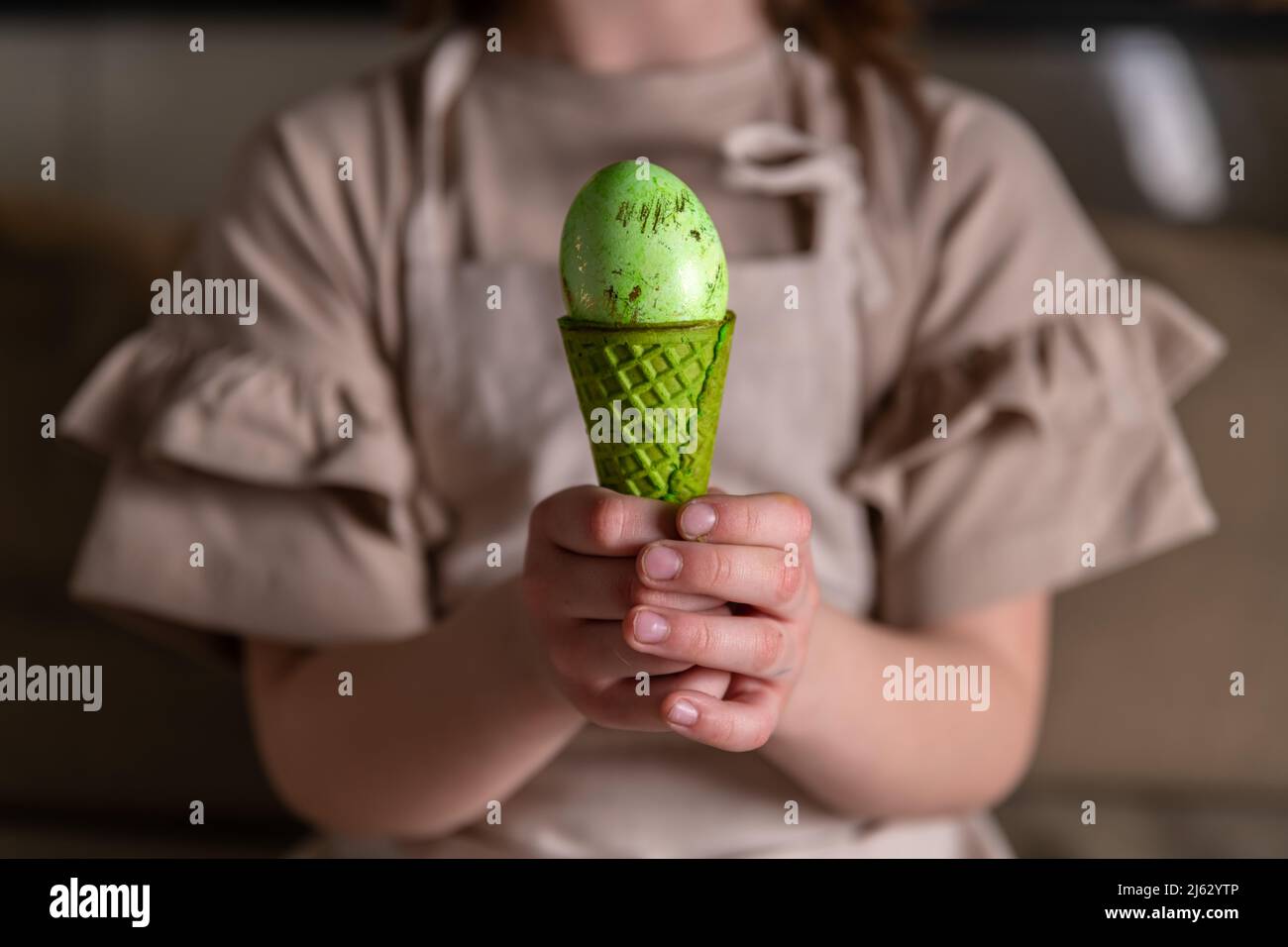 Mädchen hält ein Osterei in einem farbigen Eiskegel Stockfoto