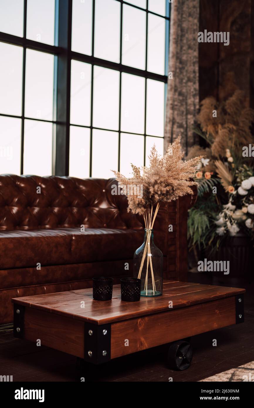 Vase mit getrockneten Blumen steht auf einem Holztisch im Innenraum Stockfoto