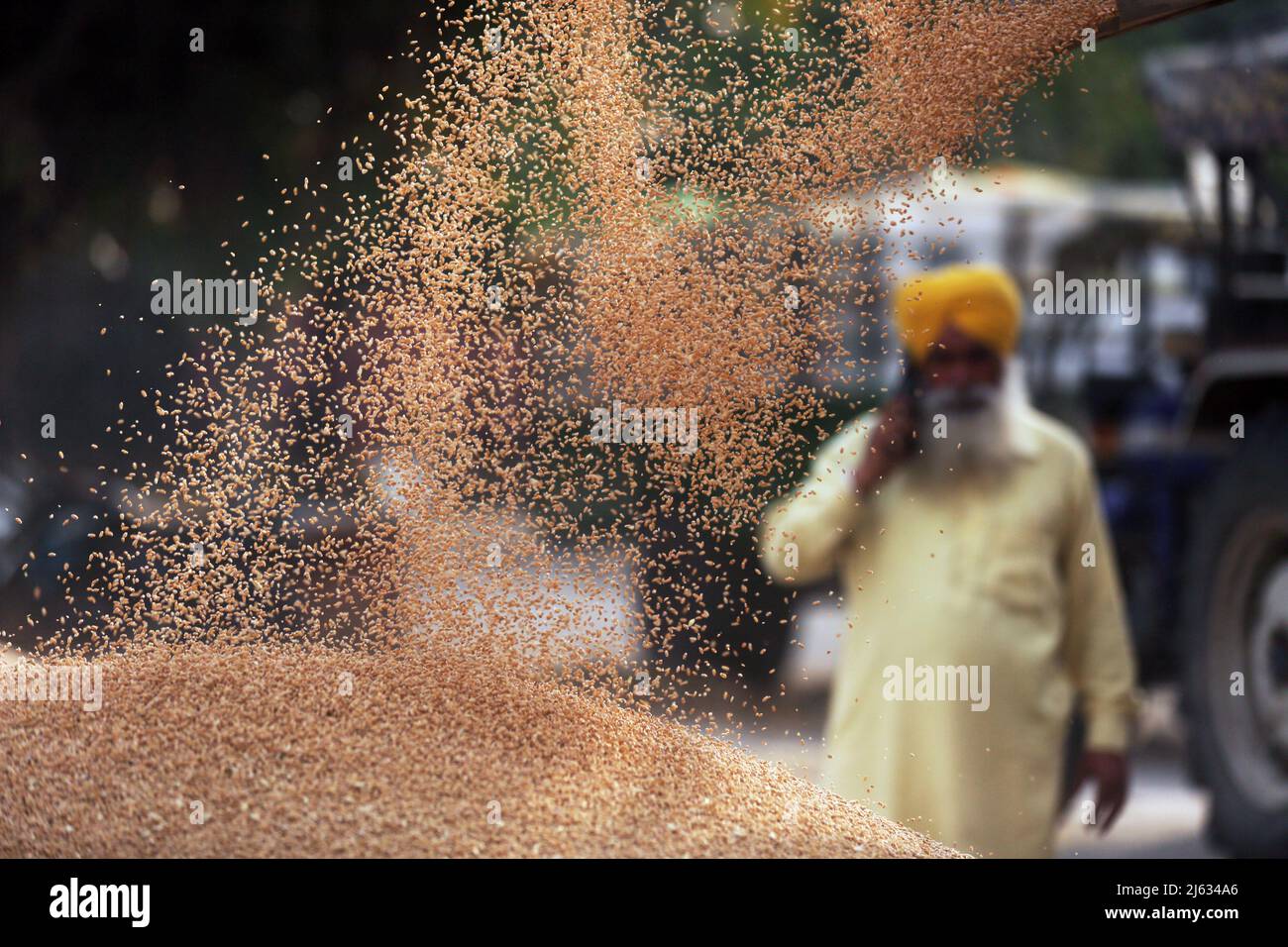 (220427) -- PEKING, 27. April 2022 (Xinhua) -- Ein Landwirt spricht auf seinem Handy, als sein frisch geernteter Weizen auf dem Getreidemarkt im Distrikt Amritsar im nördlichen Bundesstaat Punjab in Indien von einem Wagen entladen wird, 19. April 2022. Der Konflikt zwischen Russland und der Ukraine hat den Rohstoffmärkten „einen großen Schock“ verursacht und die globalen Muster von Handel, Produktion und Konsum verändert, sagte die Weltbank in einem am 26. April 2022 veröffentlichten Bericht. DIE WELTBANK warnt vor einem Anstieg der Nahrungsmittel- und Energiepreise aufgrund des Russland-Ukraine-Konflikts (Str/Xinhua) Stockfoto