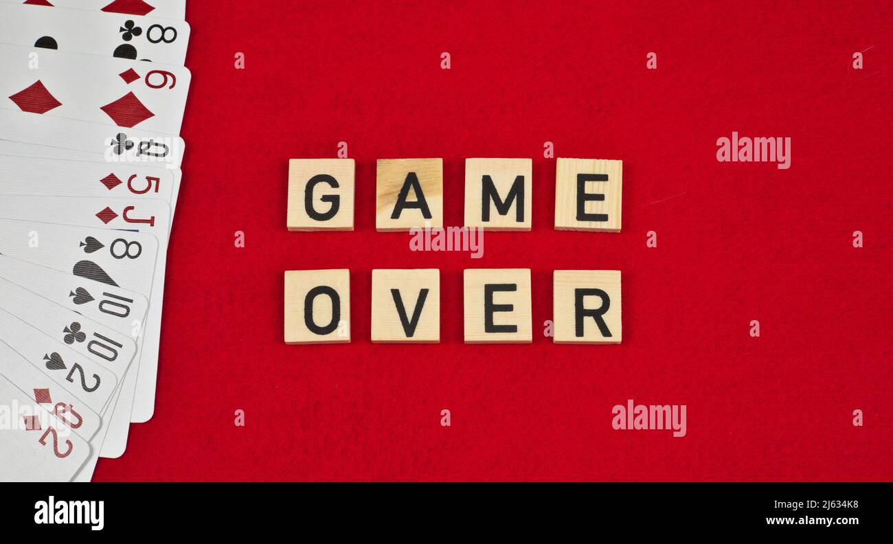 „Game Over“-Satz, bestehend aus Holztafeln und Spielkarten auf einem roten Filzhintergrund Stockfoto