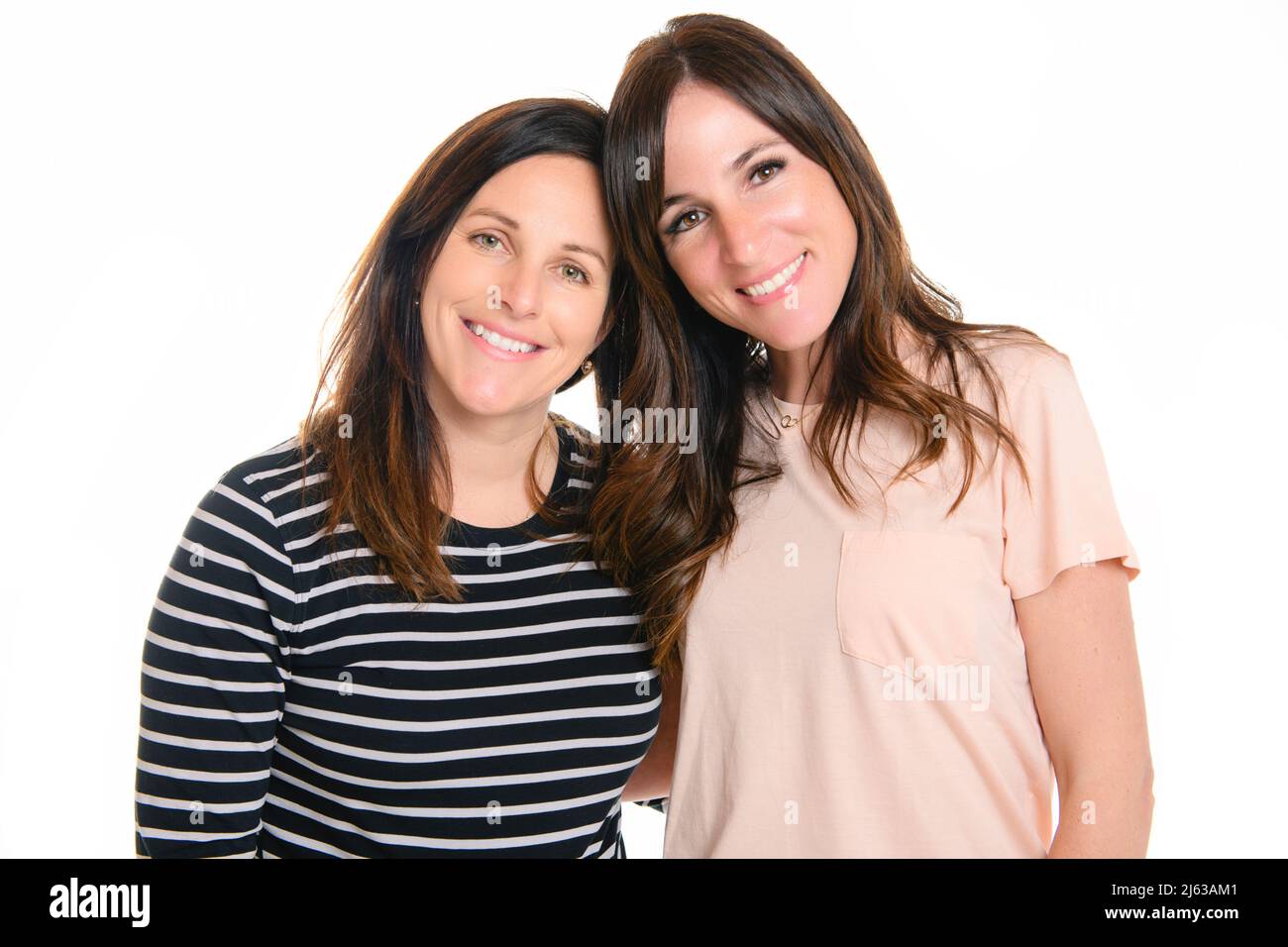 Zwei lächelnde beste Mädchen Freunde Brünette auf weißem Hintergrund. Nahaufnahme Gesicht Porträt von zwei jungen schönen Frauen. Stockfoto