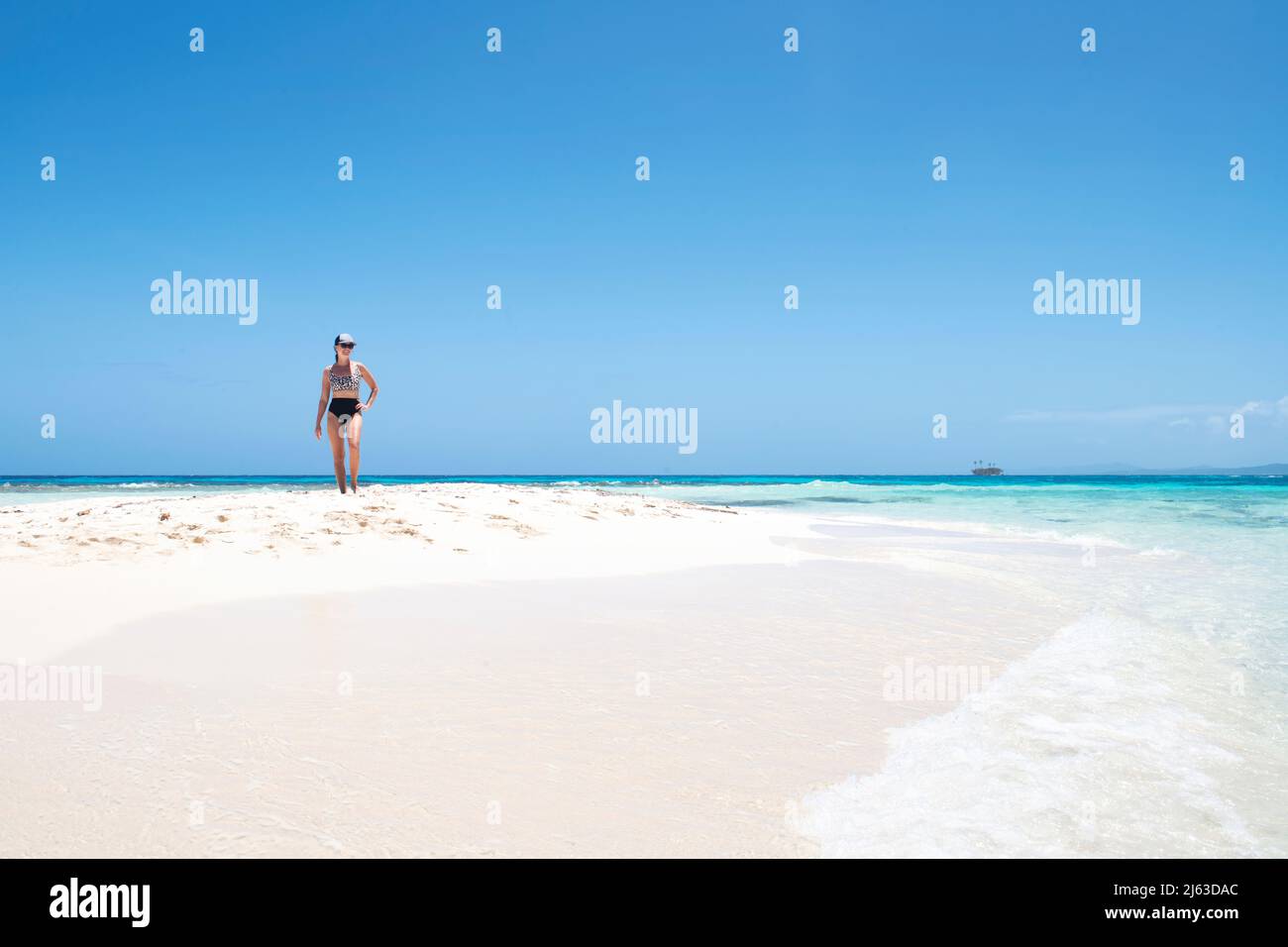 Wunderschöne Frau, die an einem karibischen Strand mit kristallklarem Wasser spazieren geht. Stockfoto