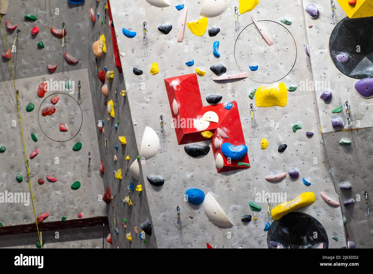 Künstliche Kletterwand mit verschiedenfarbigen Griffen. Stockfoto
