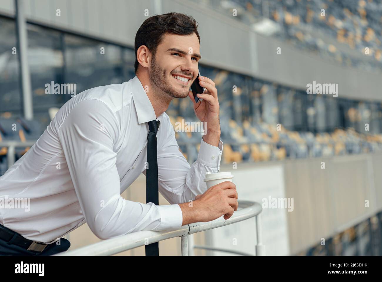Glücklicher junger Geschäftsmann im weißen Hemd ruft per Smartphone Stockfoto
