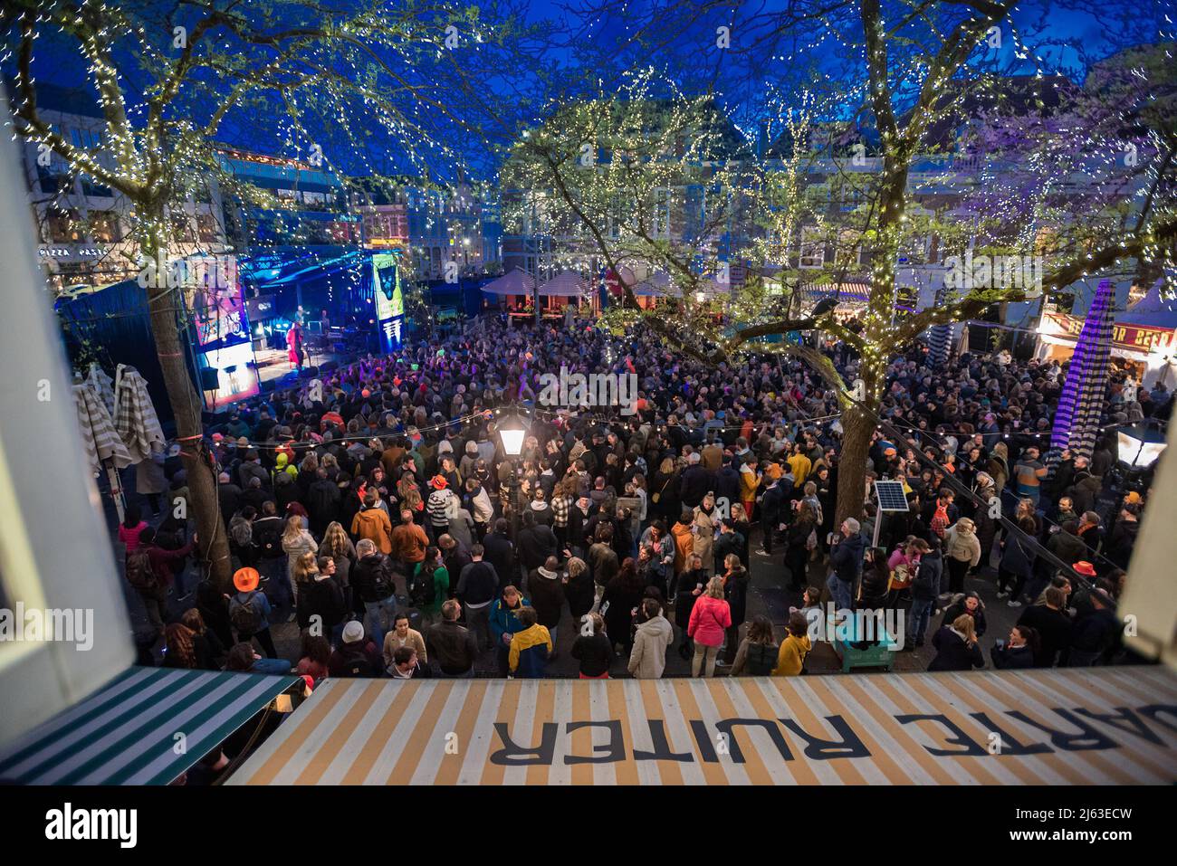 Party-Favelas in vollem Gange auf dem Grote Market in Den Haag, während des Festivals vom Zwarte Ruiter aus gesehen. DAS LEBEN, DAS ICH LEBE. Das zweitägige Festival beginnt am Abend vor dem Königstag an der Königsnacht (Koninsnacht). Das Musikfestival im Freien, das den Geburtstag des Königs feiert, findet jedes Jahr am 26. Und 27. April im Stadtzentrum von Den Haag statt. Die Feier ist eine landesweite Veranstaltung. Zahlreiche Interpreten sind gleichzeitig in ganz Den Haag auf der Bühne, und der diesjährige Eröffnungsakt von 2022 ist die ukrainische Elektro-Folk-Band ‘GO A.' Die Gruppe wurde Fünfter beim letztjährigen Eurovision Song Contest Stockfoto