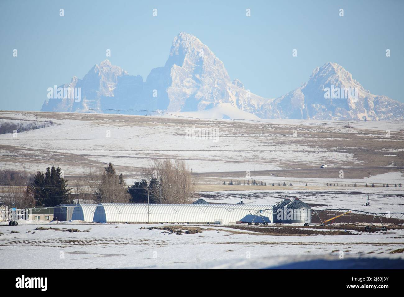 Ackerland und landwirtschaftliche Gebäude vor dem Teton-Gebirge in Idaho. Stockfoto