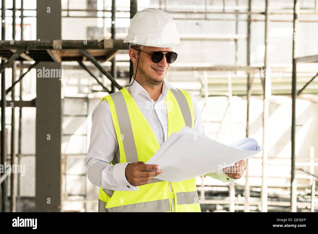 Mann Architekt trägt Sicherheitsweste mit einem Bauplan auf einer Baustelle Stockfoto