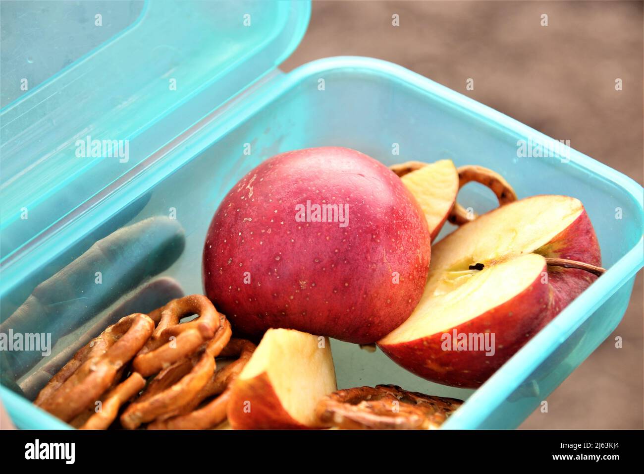 Brezeln und halbierten und in Scheiben geschnittenen Apfel in einer grünen snackbox Stockfoto