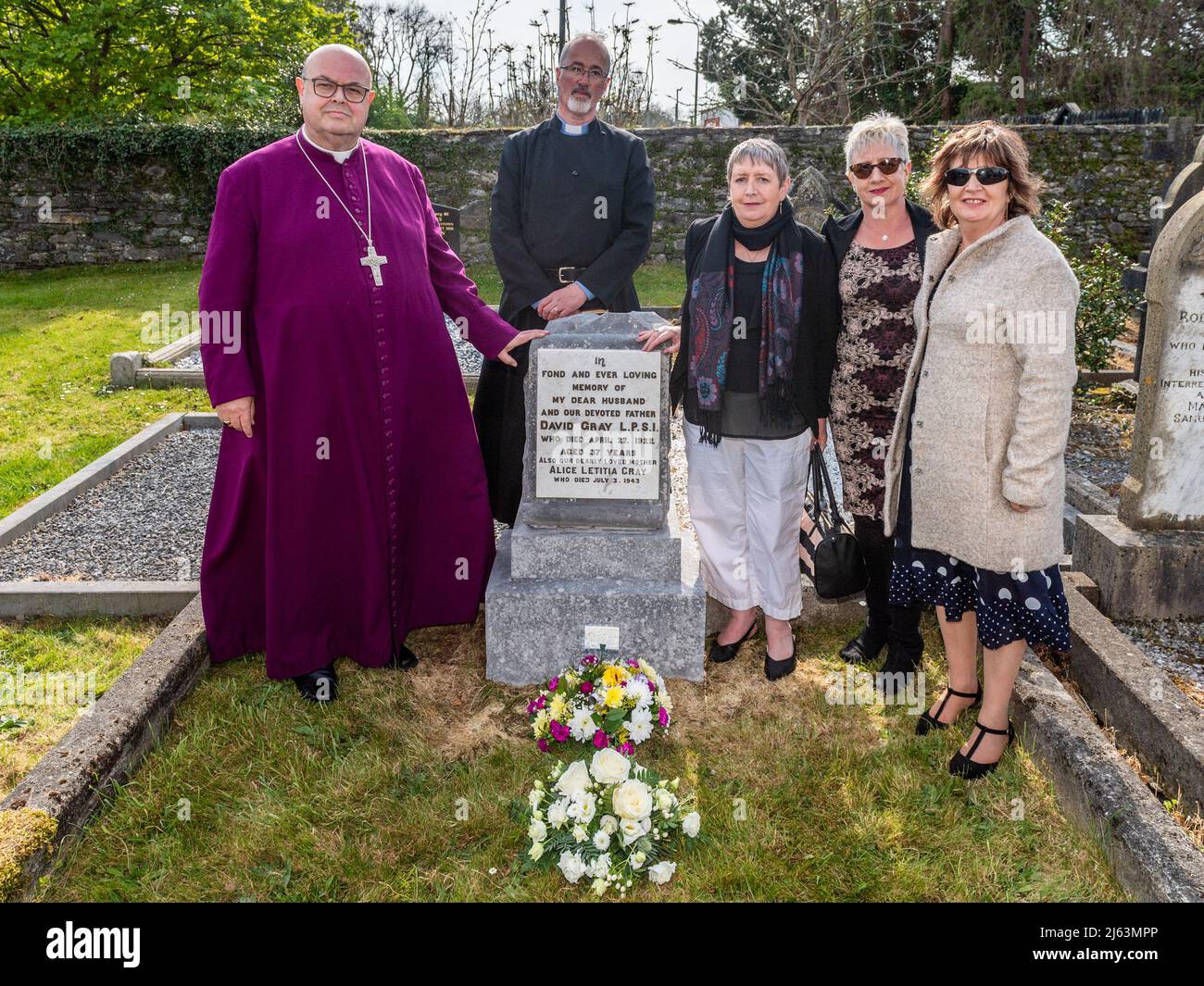 Dunmanway, West Cork, Irland. 27. April 2022. Heute ist der 100.. Jahrestag der Tötungen im Bandon Valley, bei denen 3 Männer aus Dunmanway getötet wurden. Am Grab des 37-jährigen Opfers David Gray sind Bischof von Cork, Cloyne und Ross, Dr. Paul Colton, Rektor der St. Mary's Church, Rev. Cliff Jeffers und David Grays große Nichten Jennifer Carolan, Jackie Eakins und Barbara Gargan zu sehen. Quelle: AG News/Alamy Live News Stockfoto