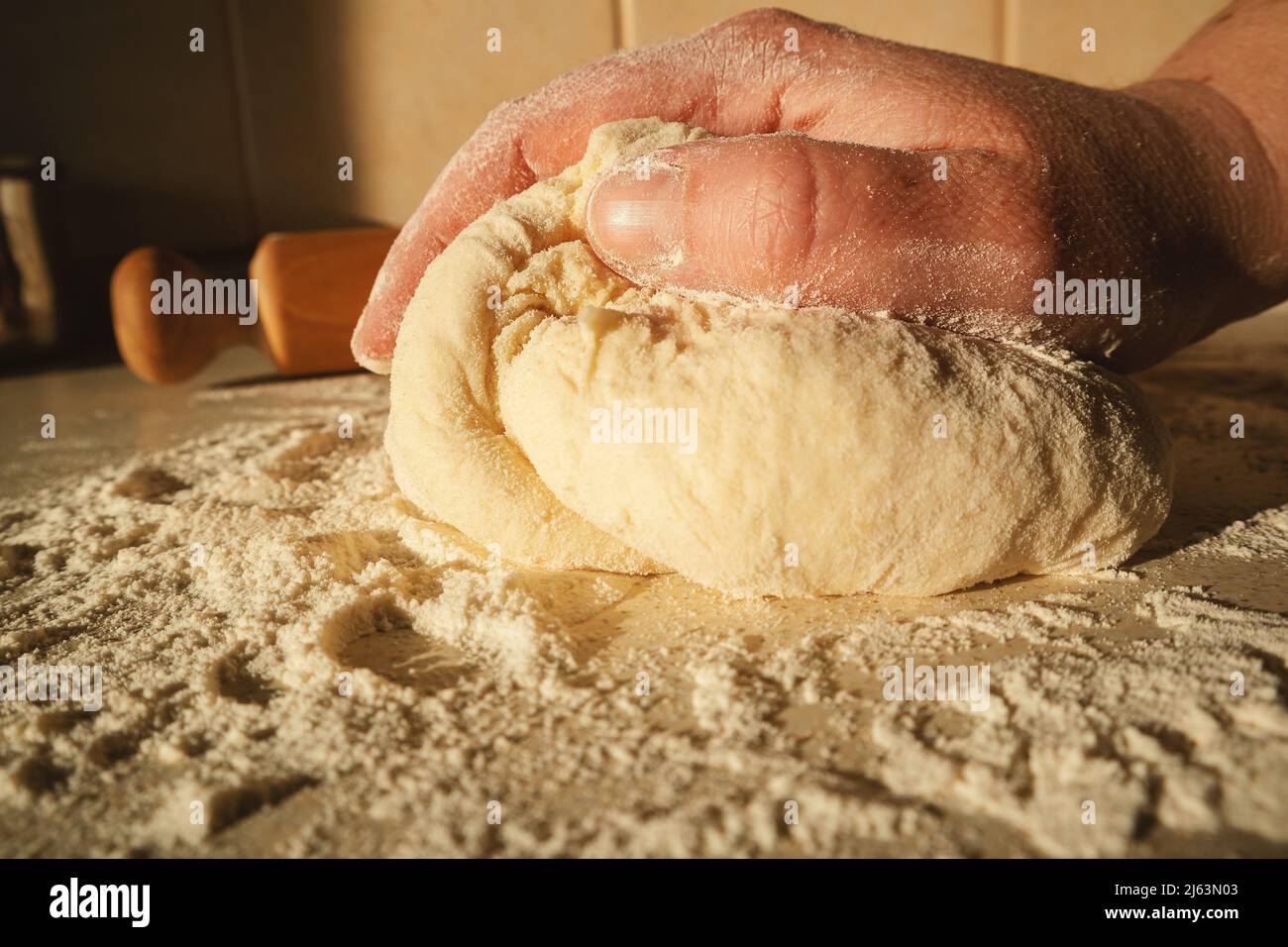 Den Teig für Brot vorbereiten, den Teig mit den Händen auf dem Tisch kneten. Stockfoto