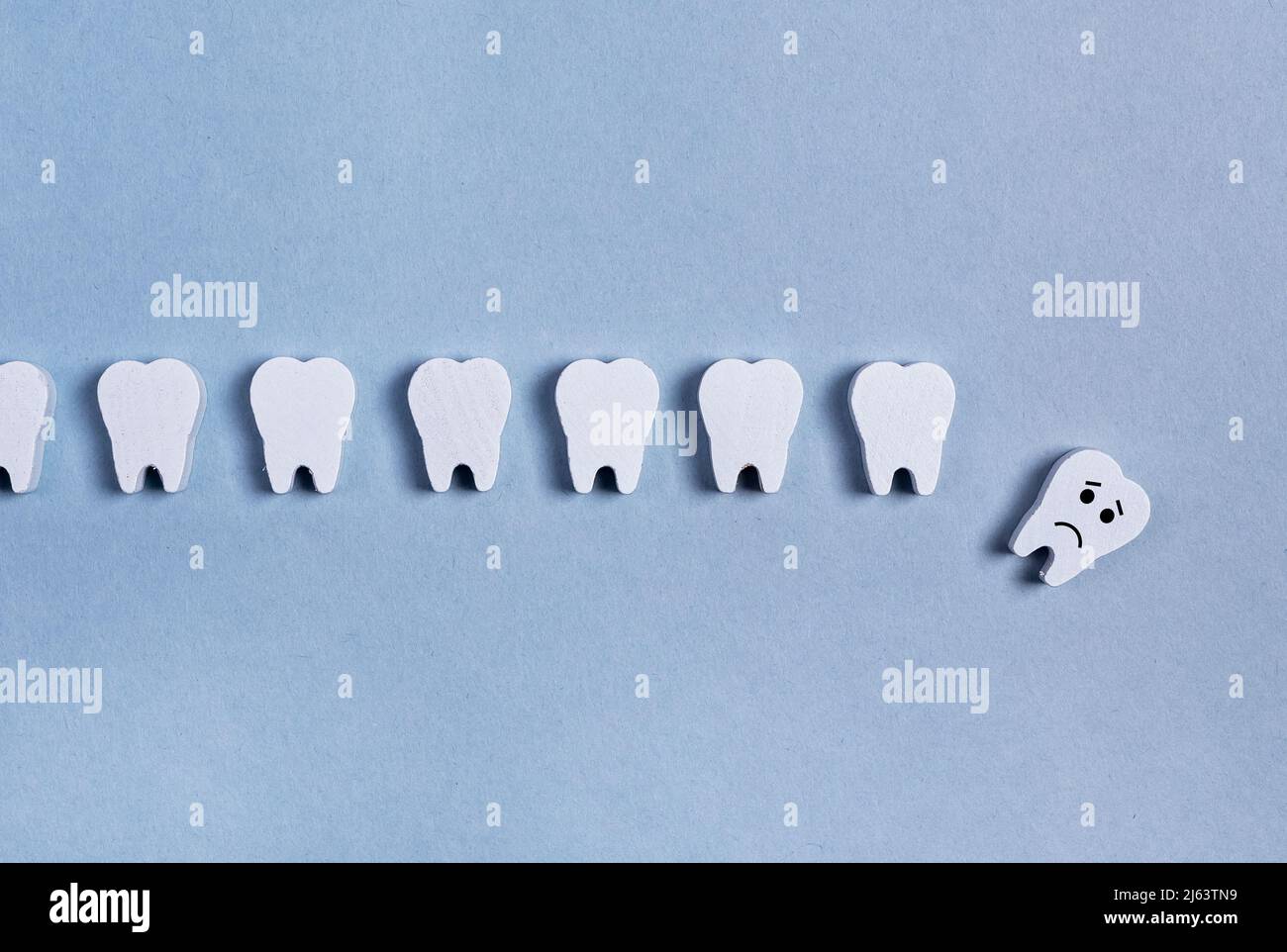 Die Zähne Reihen sich mit abgefallener Babymilch oder einem kranken Erwachsenen mit trauriger Emoji auf blauem Hintergrund. Zahnverlust durch keine professionelle Zahnpflege, schlechte Mundhygiene, Zahnfleischerkrankungen, Trauma. Hochwertige Fotos Stockfoto