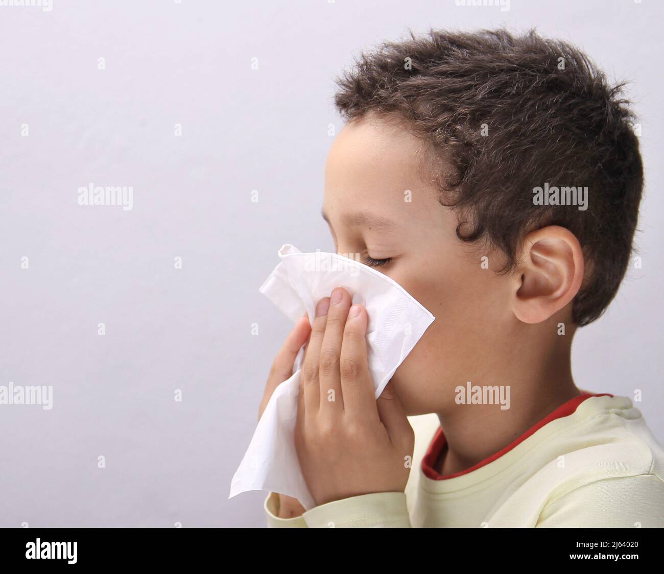 Fangen der Grippe Kind Nase bläst nach einer Erkältung mit grauem Hintergrund mit Menschen Stock Foto Stockfoto