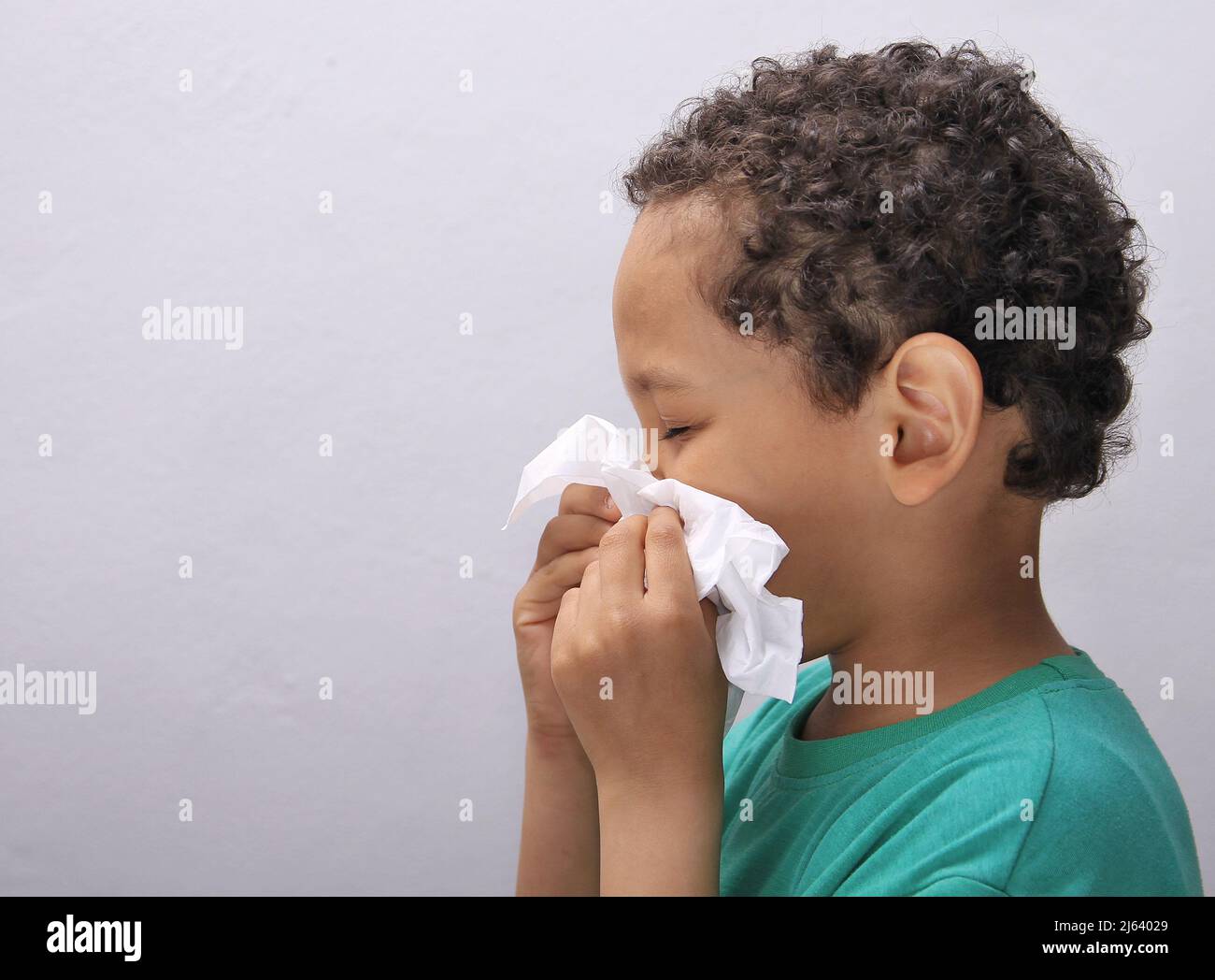 Fangen der Grippe Kind Nase bläst nach einer Erkältung mit grauem Hintergrund mit Menschen Stock Foto Stockfoto