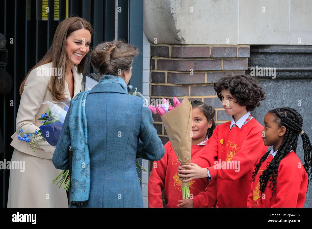 London, Großbritannien. 27. April 2022. Die königlichen Besucher werden von örtlichen Schulkindern mit Blumen überreicht. Die Prinzessin Royal, Patron, das Royal College of Hebammen (RCM), und die Herzogin von Cambridge, Patron, das Royal College of Obstetricians and Gynecologists (RCOG), werden das RCM und das RCOG-Hauptquartier in London besuchen. Das Zentrum, in dem sich eine Reihe von Frauenorganisationen befinden, die sich für die Verbesserung und Förderung der Gesundheitsversorgung von Frauen einsetzen, wurde von der RCOG entwickelt, um die Zusammenarbeit im gesamten Sektor zu fördern. Kredit: Imageplotter/Alamy Live Nachrichten Stockfoto