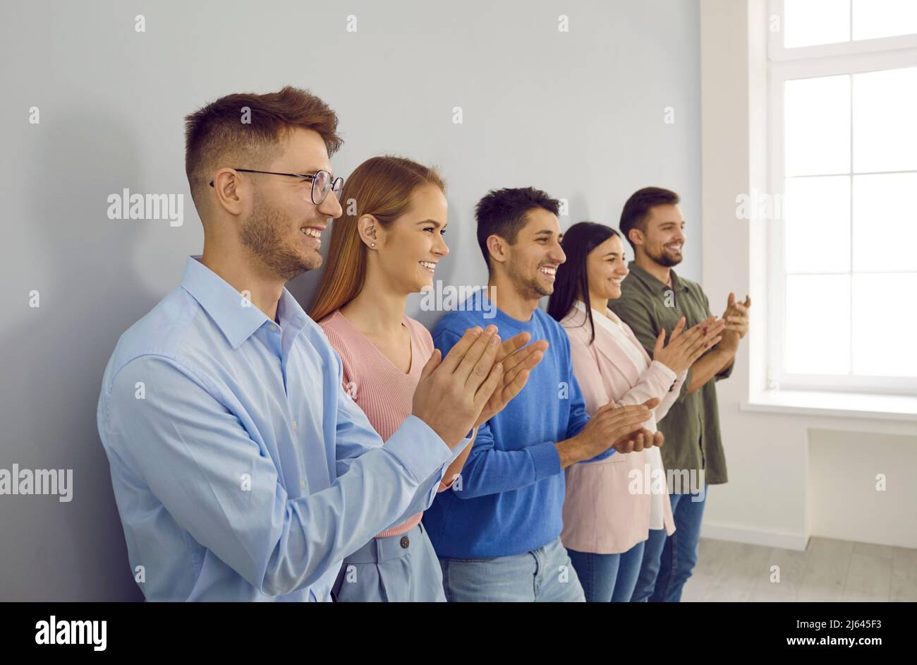 Eine Gruppe glücklicher junger Menschen applaudiert auf einer Geschäftskonferenz oder einem Teamtreffen. Stockfoto