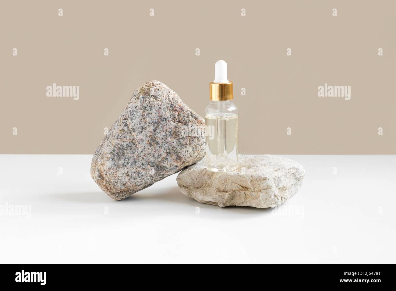 Glasflasche steht auf Stein. Natürliche Hautpflege SPA Beauty-Produkt-Design. Mineralische Bio-Öl-Kosmetik auf beigem Hintergrund. Modell. Stockfoto