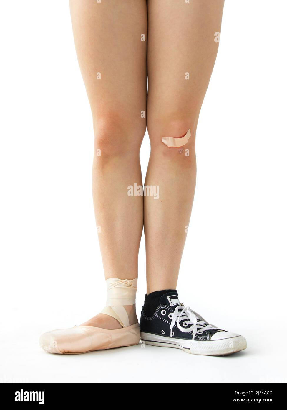 Die Beine einer jungen Frau mit einem Fuß, der einen Ballettschuh trägt und der andere einen Sneaker, um die vielfältigen Interessen einer Frau zu veranschaulichen. Stockfoto