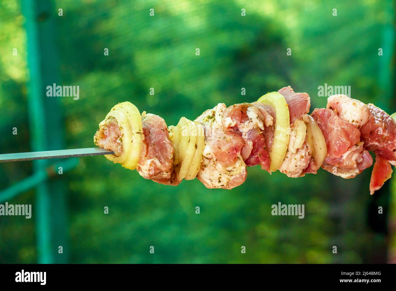 Rohes mariniertes Fleisch und Zwiebeln auf einem Spieß. Der Kebab wird für das Kochen auf einem offenen Feuer vorbereitet. Stockfoto