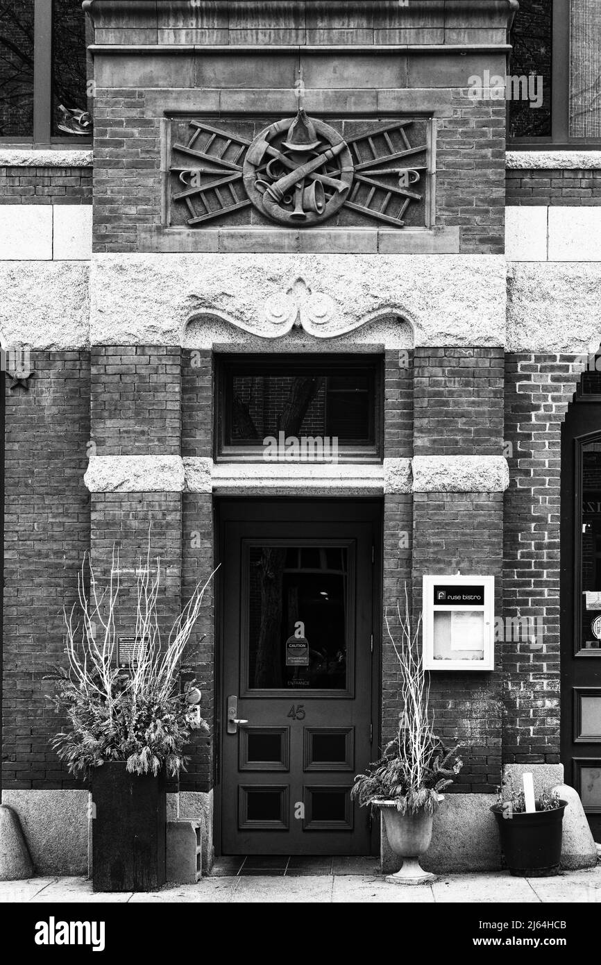 Ein altes Feuerhaus, das in ein Restaurant umgewandelt wurde. Über der Tür befindet sich die in Stein gemeißelte Insignie des Feuerwehrmans. Lowell, Massachusetts. Stockfoto