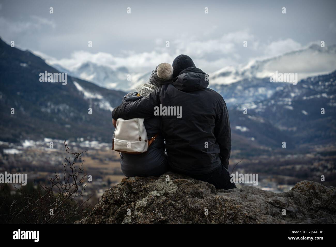 Junges Paar, das sich anlehnt, während es im Winter die wunderschönen schneebedeckten Berge in Briancon beobachtet. Stockfoto