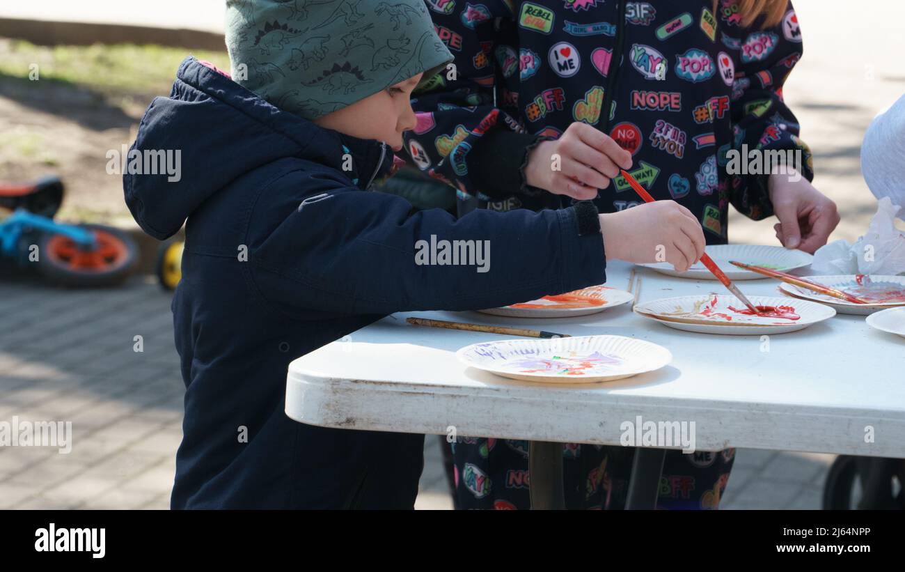 Olaine, Lettland - 18. April 2022. Kinder malen mit Farben. Outdoor-Farb-Kreativworkshop für Familien mit Kindern im Frühjahr an Ostern festlichen tim Stockfoto