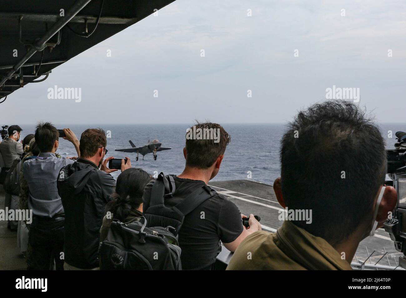 PHILIPPINISCHE SEE (23. April 2022) Mitglieder internationaler Medien Filmen den Flugbetrieb an Bord des Flugzeugträgers USS Abraham Lincoln (CVN 72) der Nimitz-Klasse. Die Abraham Lincoln Strike Group befindet sich im geplanten Einsatzgebiet der US-Flotte für 7., um die Interoperabilität durch Allianzen und Partnerschaften zu verbessern und gleichzeitig als reaktionsfähige Truppe zur Unterstützung einer freien und offenen Region im Indo-Pazifik-Raum zu dienen. (USA Navy Foto von Mass Communication Specialist Seaman Apprentice Julia Brockman) Stockfoto