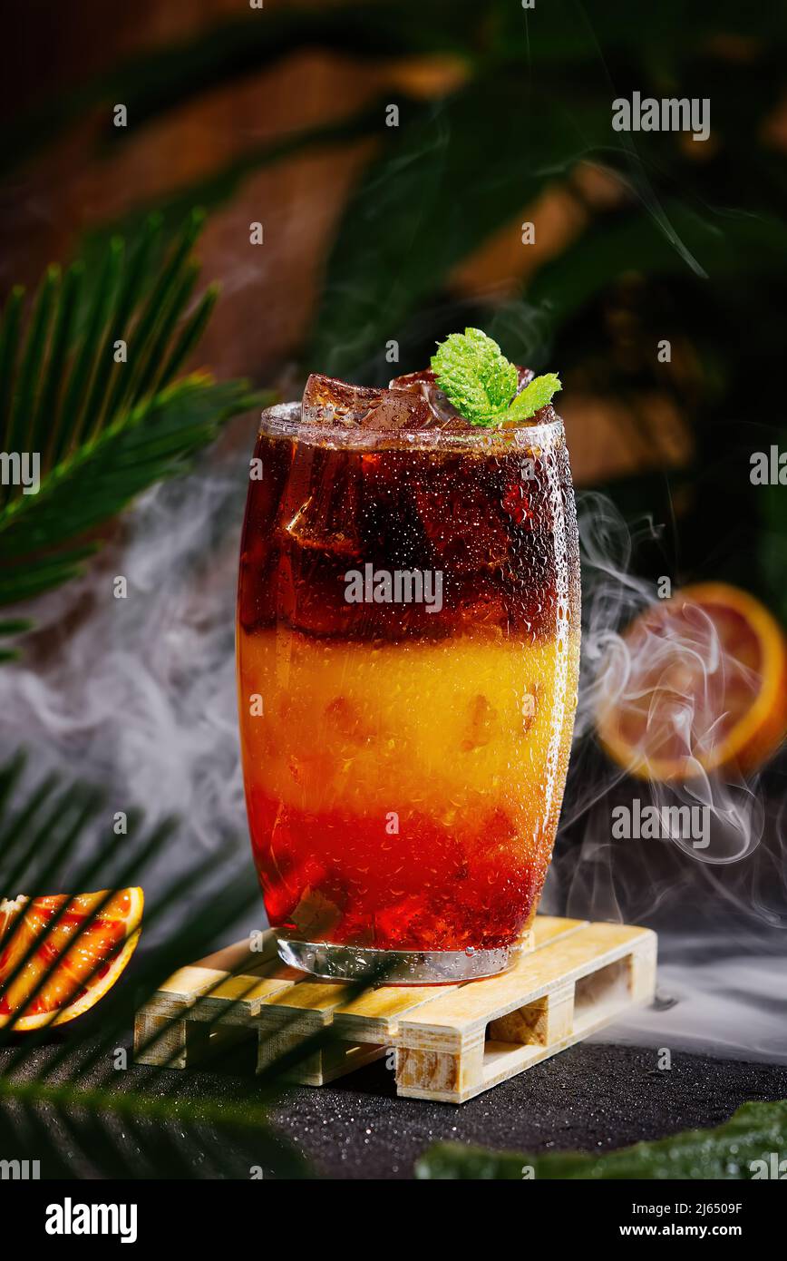 Bumble Kaffee mit Eis auf einem dunklen tropischen Hintergrund. Espresso, Orangensaft und Sirup in Schichten Stockfoto