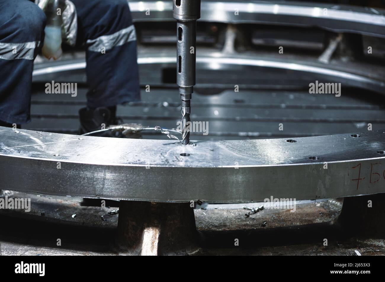 Arbeiter macht Loch in Metallring mit Radialbohrmaschine Stockfoto
