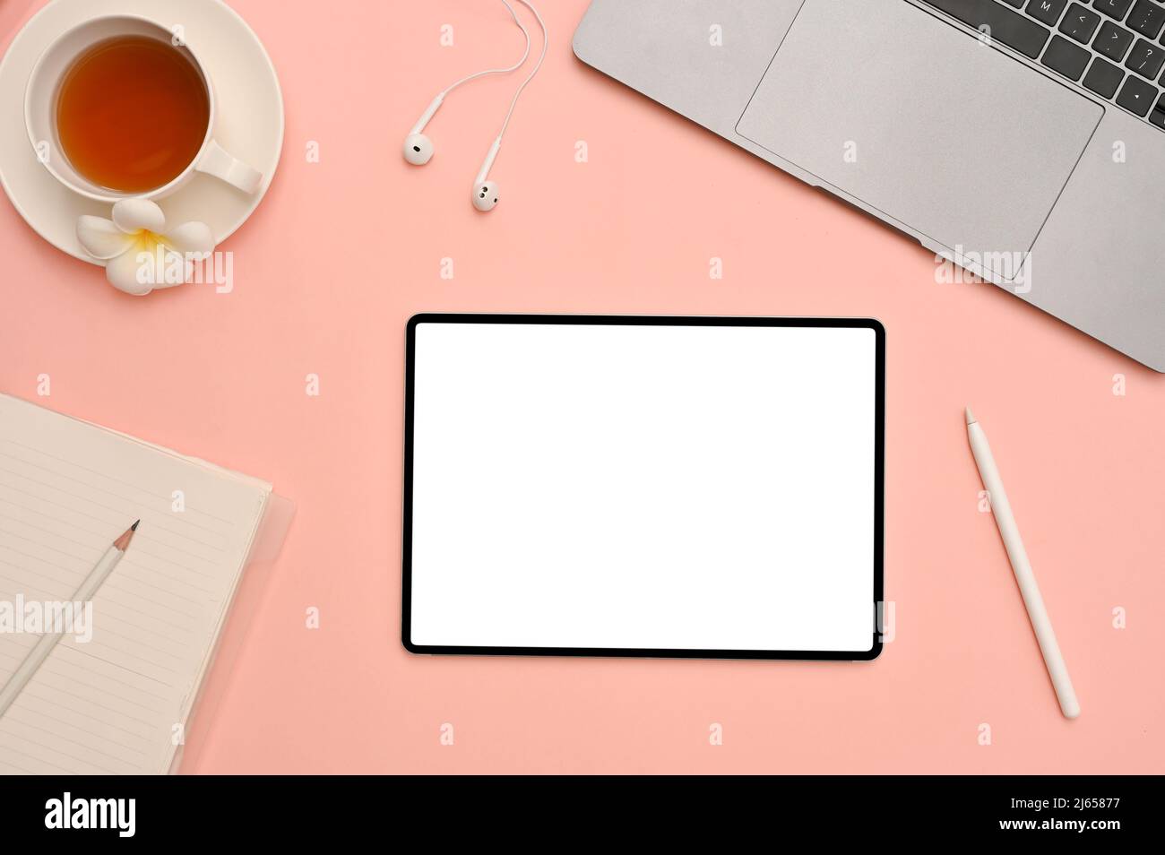 Schöner femininer Arbeitsplatz, Büroschreibtisch von oben mit Laptop-Computer, Teetasse, Schreibwaren und weißem Digital-Tablet-Modell auf rosa Hintergrund. Stockfoto
