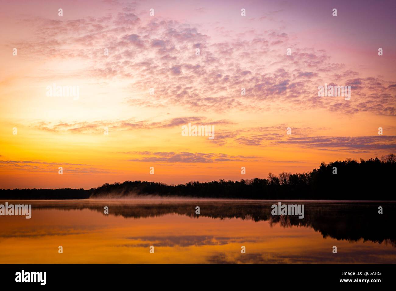 Hannover, Deutschland. 28. April 2022. Der Himmel über dem Altwarmbüchensee leuchtet bei Sonnenaufgang gelb-orange, während Bodennebel über der Wasseroberfläche driftet. Quelle: Moritz Frankenberg/dpa/Alamy Live News Stockfoto