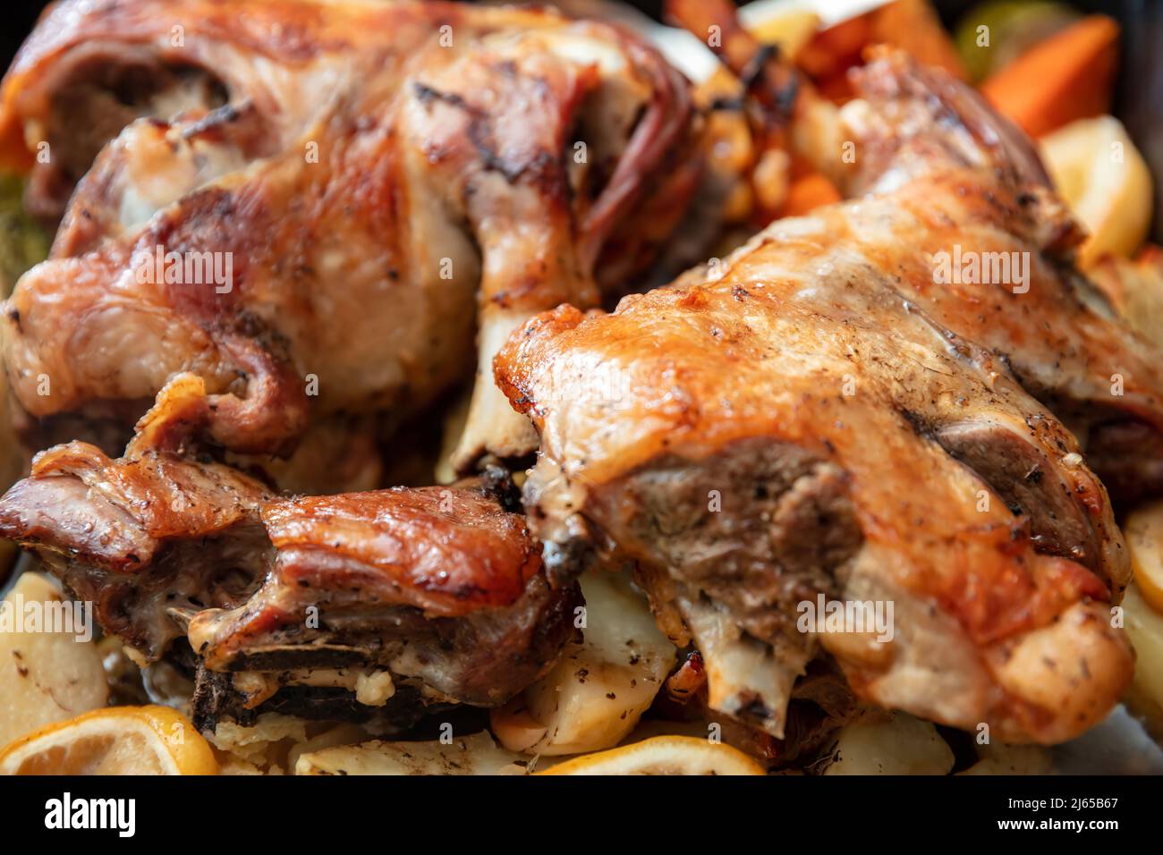 Lammkeule mit Knochen gebacken mit Kartoffeln und Kräutern im Ofen. Traditionelles griechisches Osteressen, mariniertes Ziege- oder Schaffleisch, zubereitet mit frischem Gemüse. Schließen Stockfoto