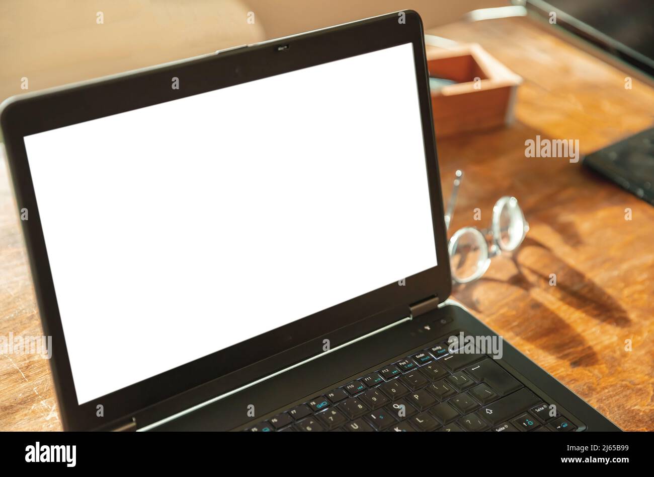 Computerbildschirmmockup. Laptop offen mit weißem leeren Bildschirm auf einem Holzschreibtisch, Bürohintergrund, Kopierraum, Präsentationsvorlage bewerben Stockfoto