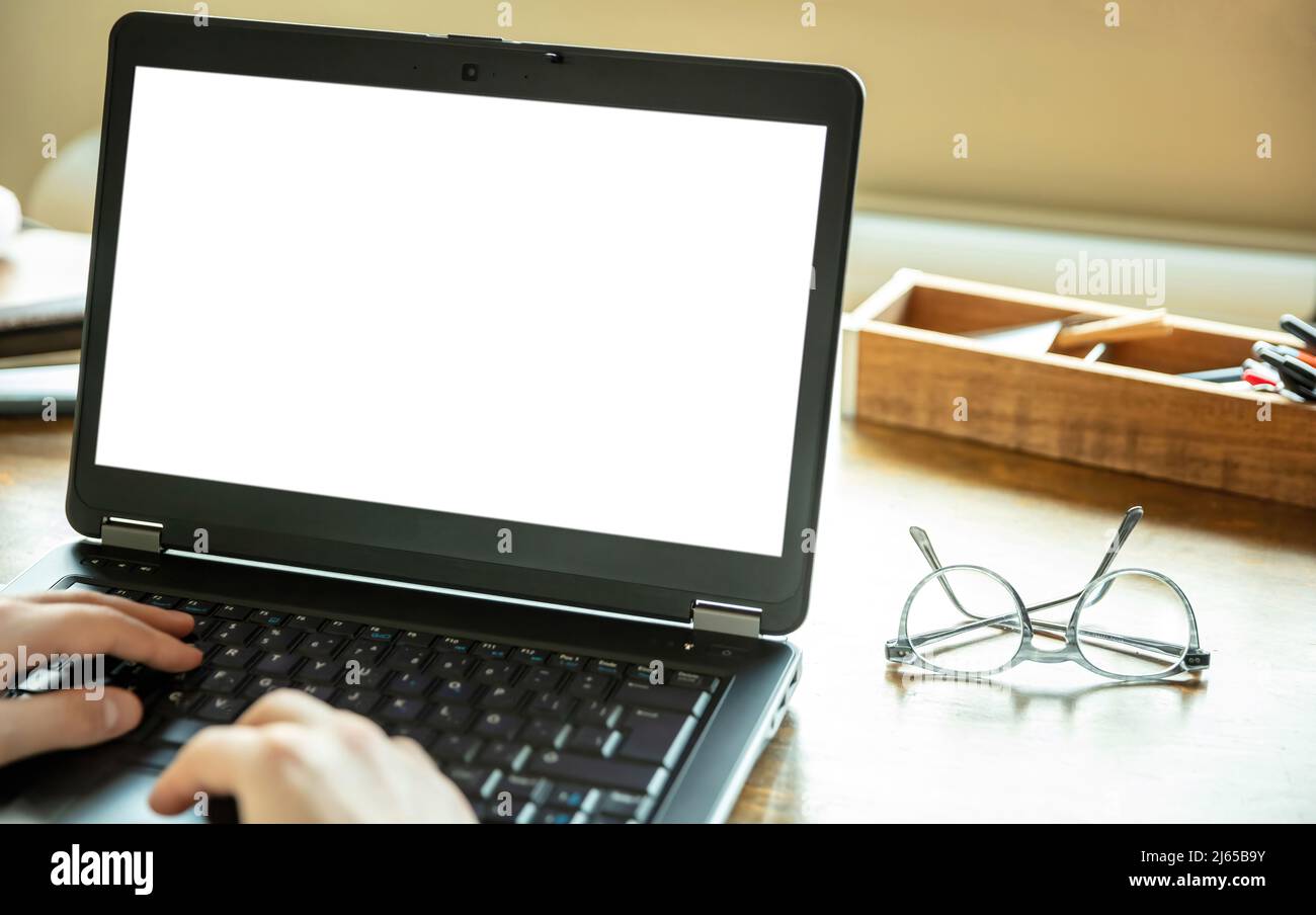 Laptop offen mit weißem leeren Bildschirm auf einem Holzschreibtisch, Bürohintergrund, Kopierraum, Präsentationsvorlage bewerben. Computerbildschirmmockup. Stockfoto