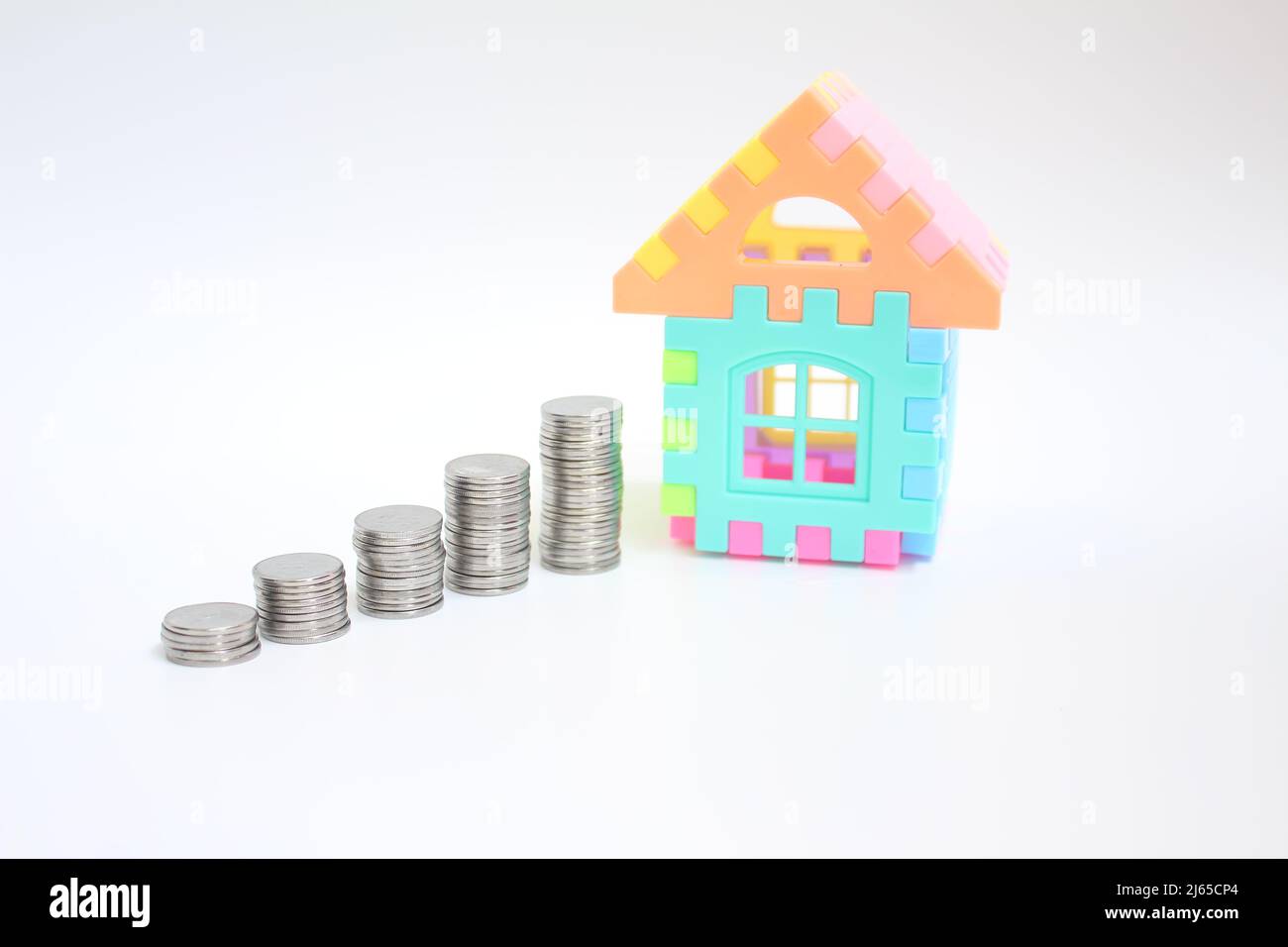 Münzen Geld und ein Haus zeigen, dass Planung, Sparen und Ausgaben wichtig sind, bevor sie Entscheidungen treffen. Geschäfts- und Versicherungskonzept. Stockfoto