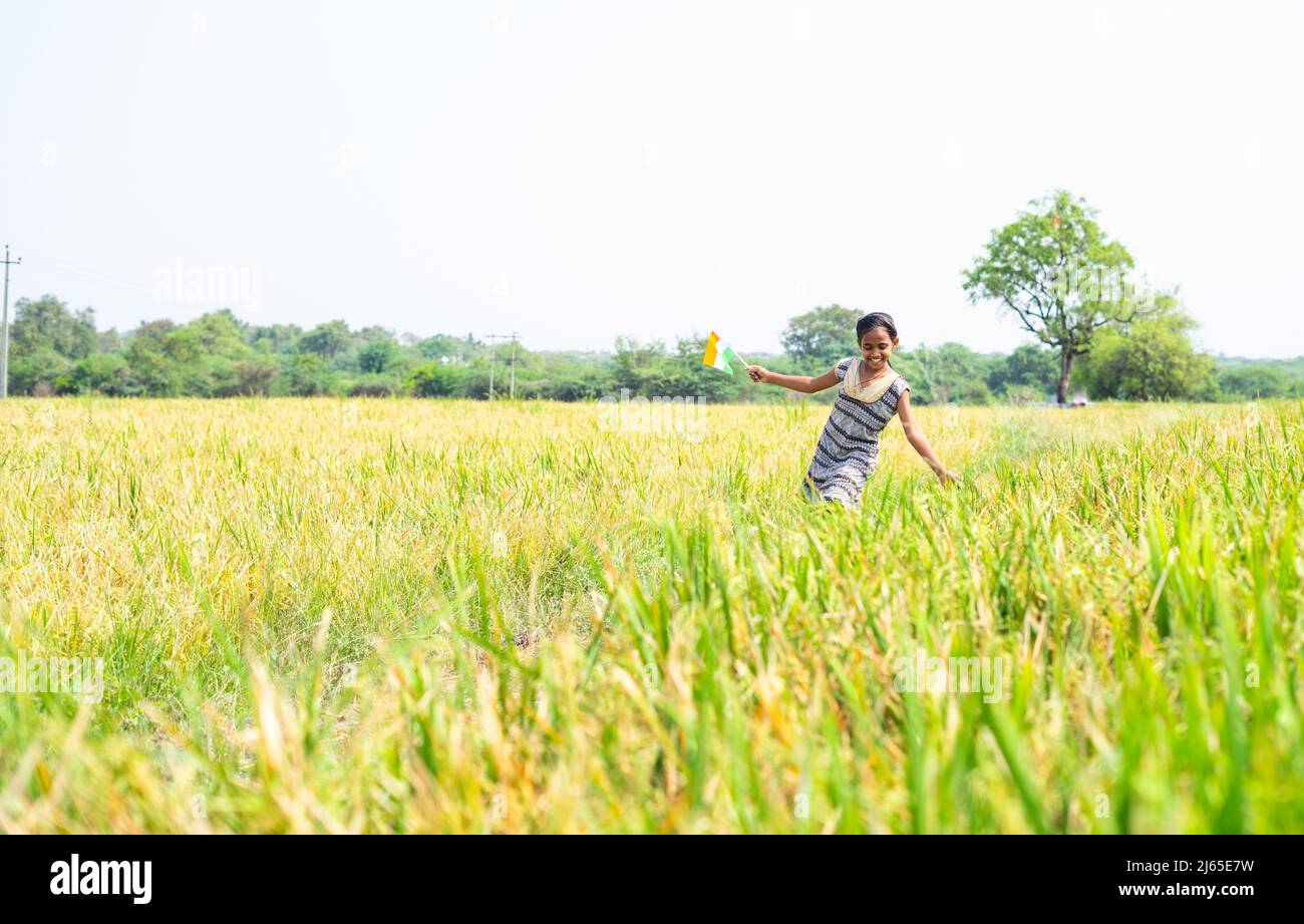 Tanzende junge Dorf Mädchen Kind, indem sie indische Flagge auf Pady Landwirtschaft Feld - Konzept der Freiheit, republik oder Unabhängigkeit Feier und ländlichen Stockfoto