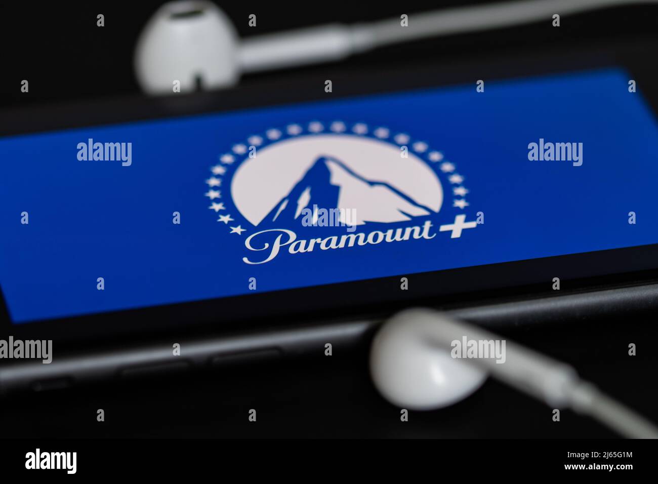 Rheinbach, Deutschland 28. April 2022, das Markenlogo des Streaming-Dienstes 'Paramount +' auf dem Display eines Smartphones mit Kopfhörern Stockfoto