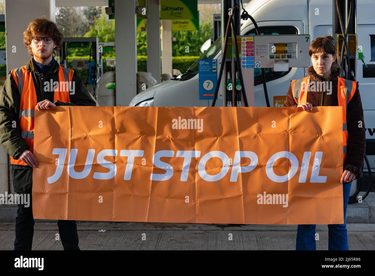 Kent, Großbritannien. 28. April 2022 Demonstranten von Just Stop Oil blockieren die BP-Garage bei Clacket Lane Services am M25. Sie fordern die Regierung auf, die Gewinnung neuer fossiler Brennstoffe sowie die Gas- und Ölbohrungen zu beenden und sie zu drängen, stattdessen in erneuerbare Energien zu investieren. Demonstranten zerschlagen das Glas auf Benzinpumpen und Graffiti über der Front und kleben sich schließlich an die Pumpen Credit: Denise Laura Baker/Alamy Live News Credit: Denise Laura Baker/Alamy Live News Stockfoto