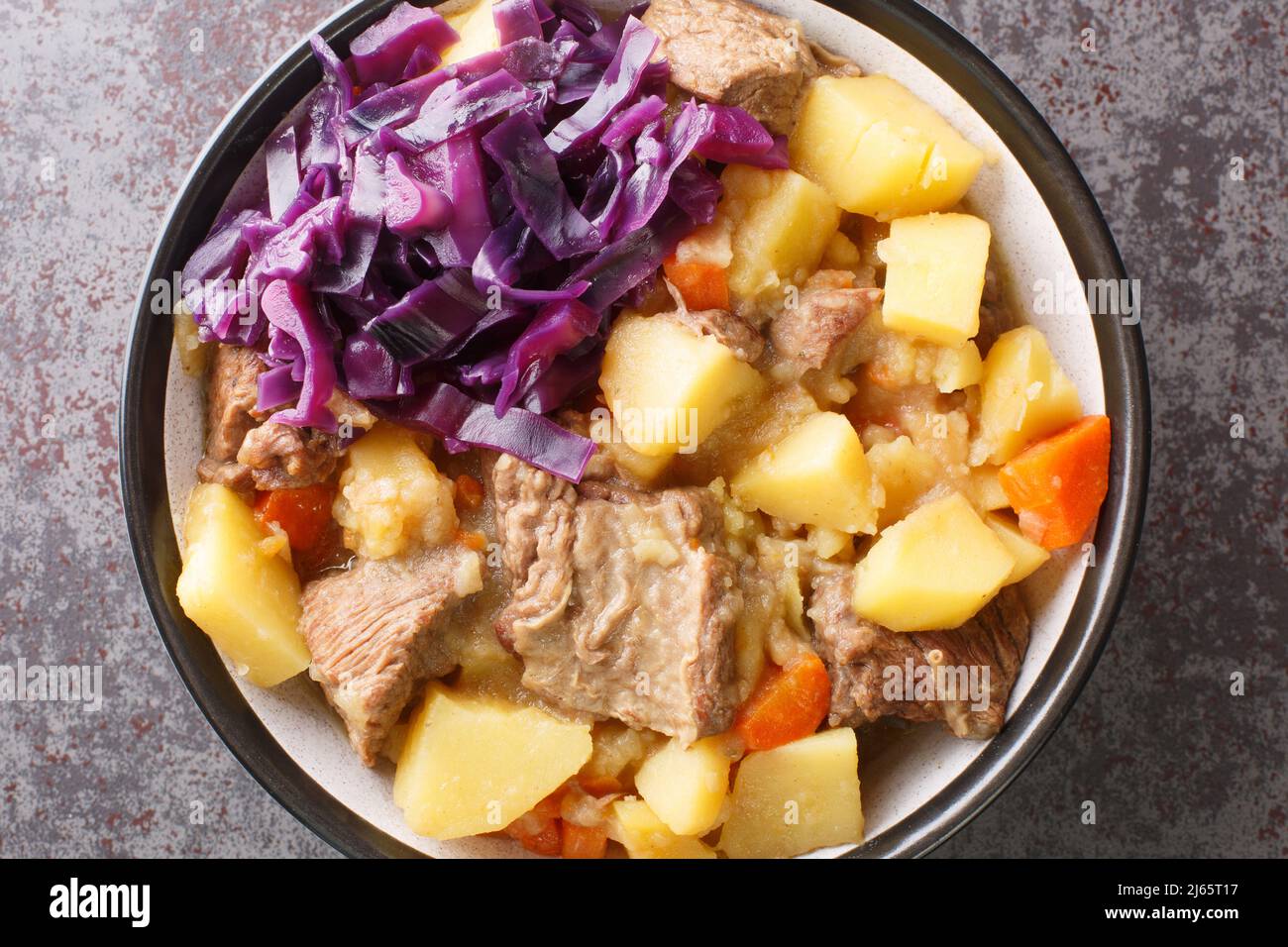 Scouse ist ein Eintopf mit Fleisch und Gemüse, serviert mit eingelegtem Kohl aus nächster Nähe auf einem Teller auf dem Tisch. Horizontale Draufsicht von oben Stockfoto