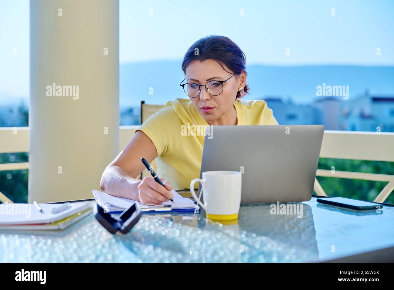 Frau mittleren Alters, die in einem Heimbüro auf einer Terrasse arbeitet. Stockfoto