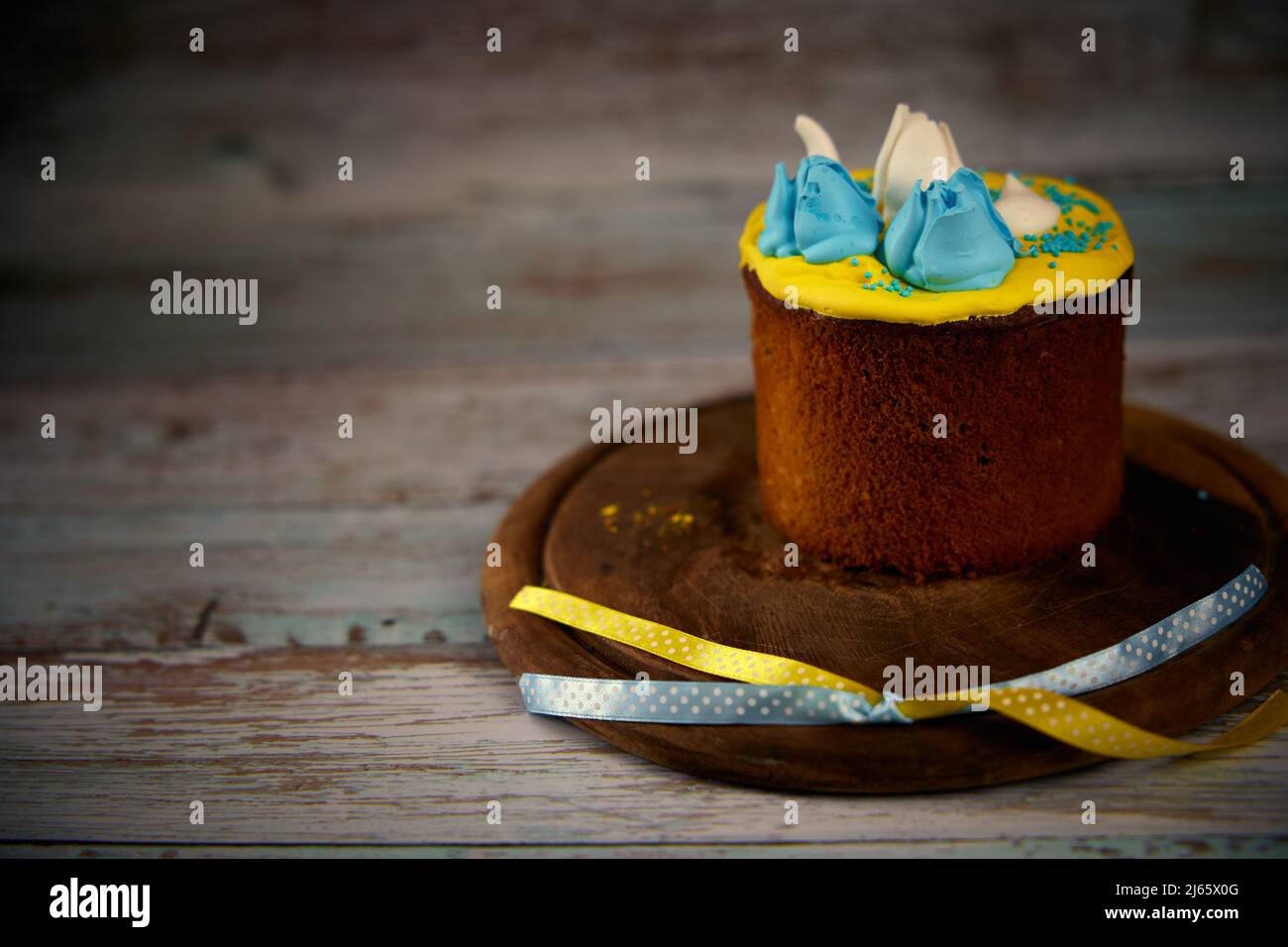 Osterkarte. Osterkuchen mit Creme in den Farben der ukrainischen Flagge auf einem Holzbrett dekoriert Stockfoto