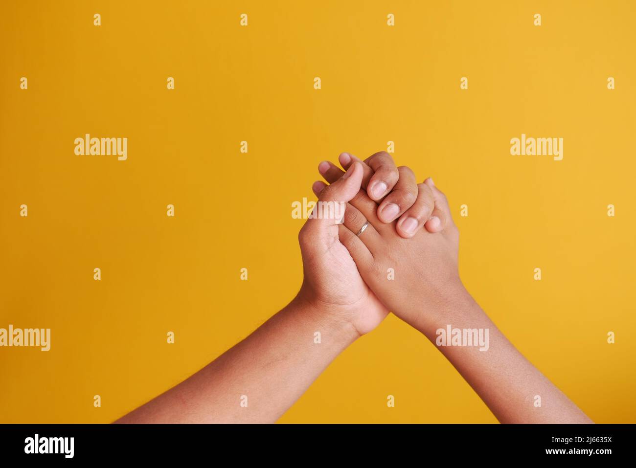 Vater hält seine kleine Junge Hand auf gelbem Hintergrund Stockfoto