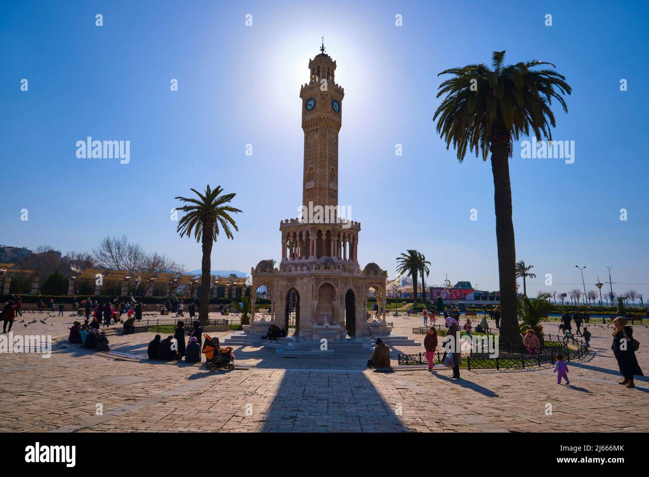Hintergrundbeleuchteter Blick auf den Wahrzeichen-Uhrenturm mit Palmen. Am Konak Meydanı, Platz in Izmir, Türkei. Stockfoto