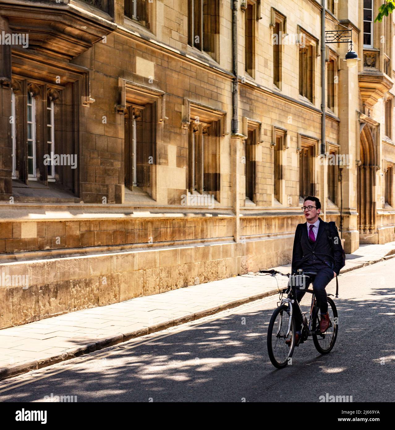 Oxford, Großbritannien; Mann, der in einem Anzug ohne Hände am Lenker unterwegs ist, die Turn Street hinunter, mit Exeter College hinter sich Stockfoto