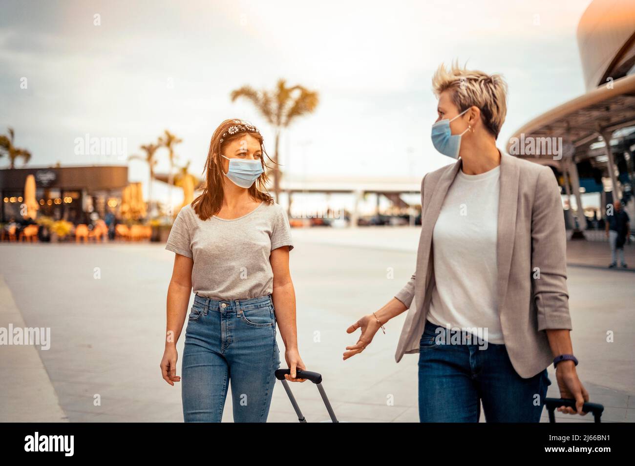 Reisende Frauen in Schutzmasken reden beim Verlassen des Flughafens am Zielort Stockfoto