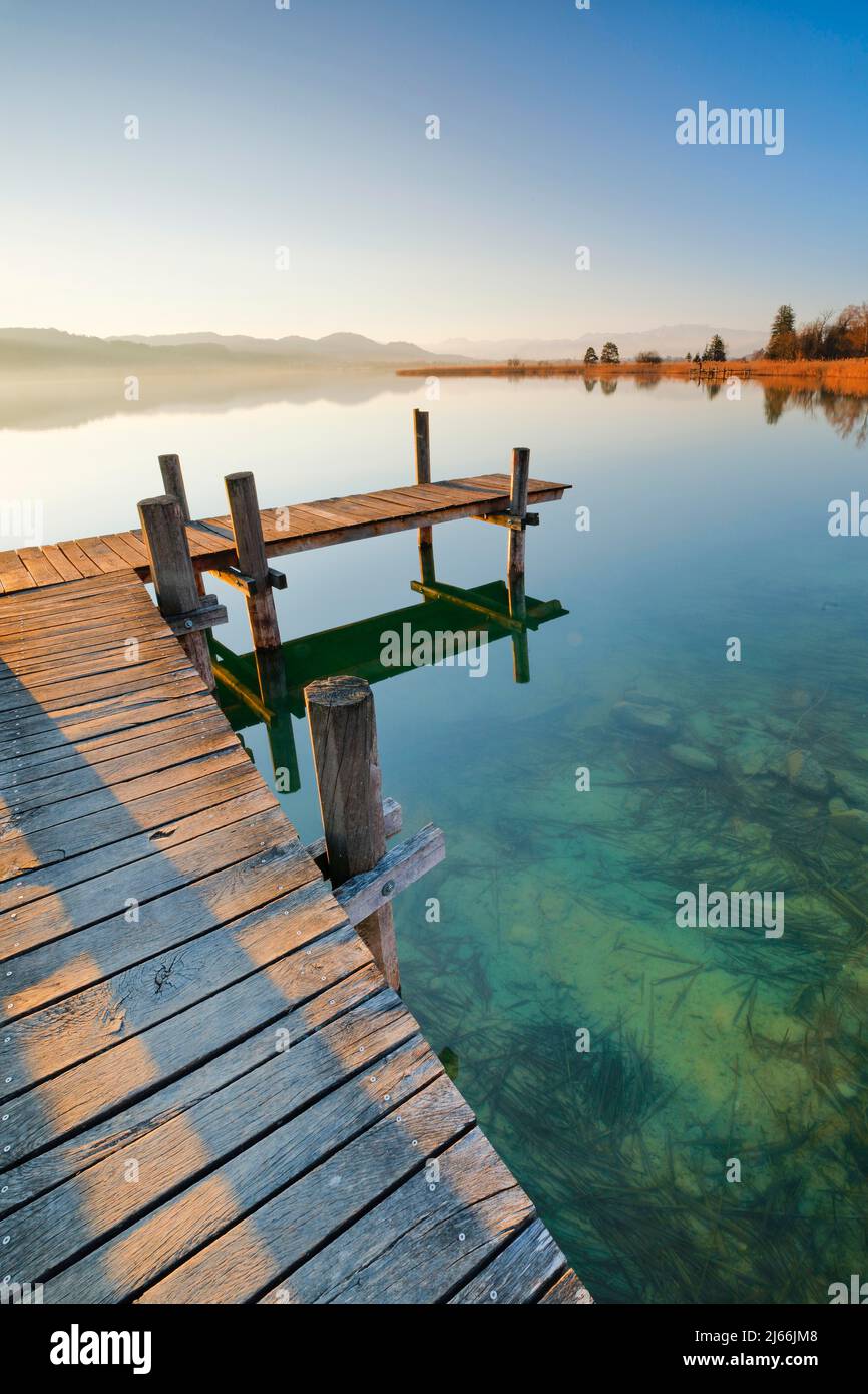 Holzsteg am Pfäffikersee bei Sonnenaufgang mit Blick zum Bachtel und Gletscher im Hintergrund, Pfäffikon, Kanton Zürich, Schweiz Stockfoto